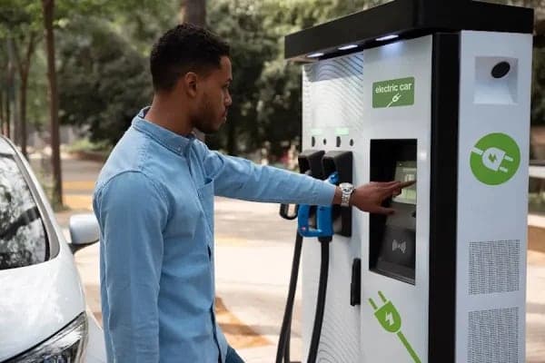 A driver using the touchscreen on a public fast-charging pillar